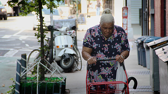 Photograph of an elderly woman pushing a cart on the Lower East Side