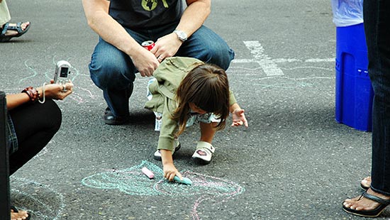 A child drawing on the street with sidewalk chalk