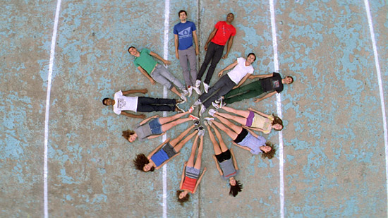 People lying on a concrete slab with their feet touching, forming a circle