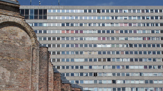 The facade of a brick building foregrounded over a background of a modern office block