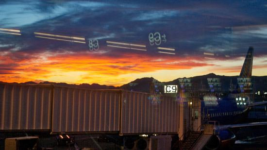 The view out of an airport terminal window, looking at a jet bridge