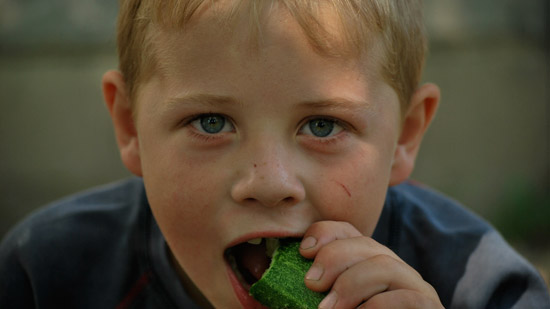 Photograph of a child eating a cucumber