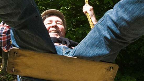 An elderly person on a wooden swing